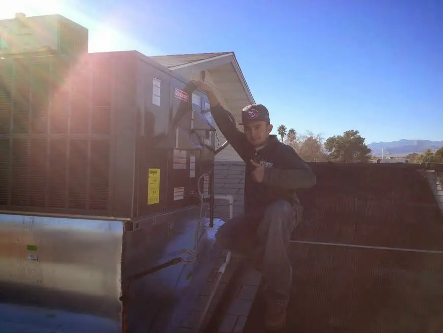 HVAC technician performing AC Tune-Up on a rooftop unit in Grosse Pointe Woods