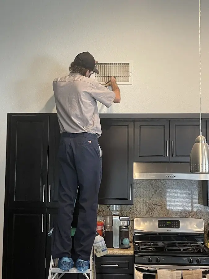 Technician inspecting an air vent during HVAC service in Grosse Pointe Woods